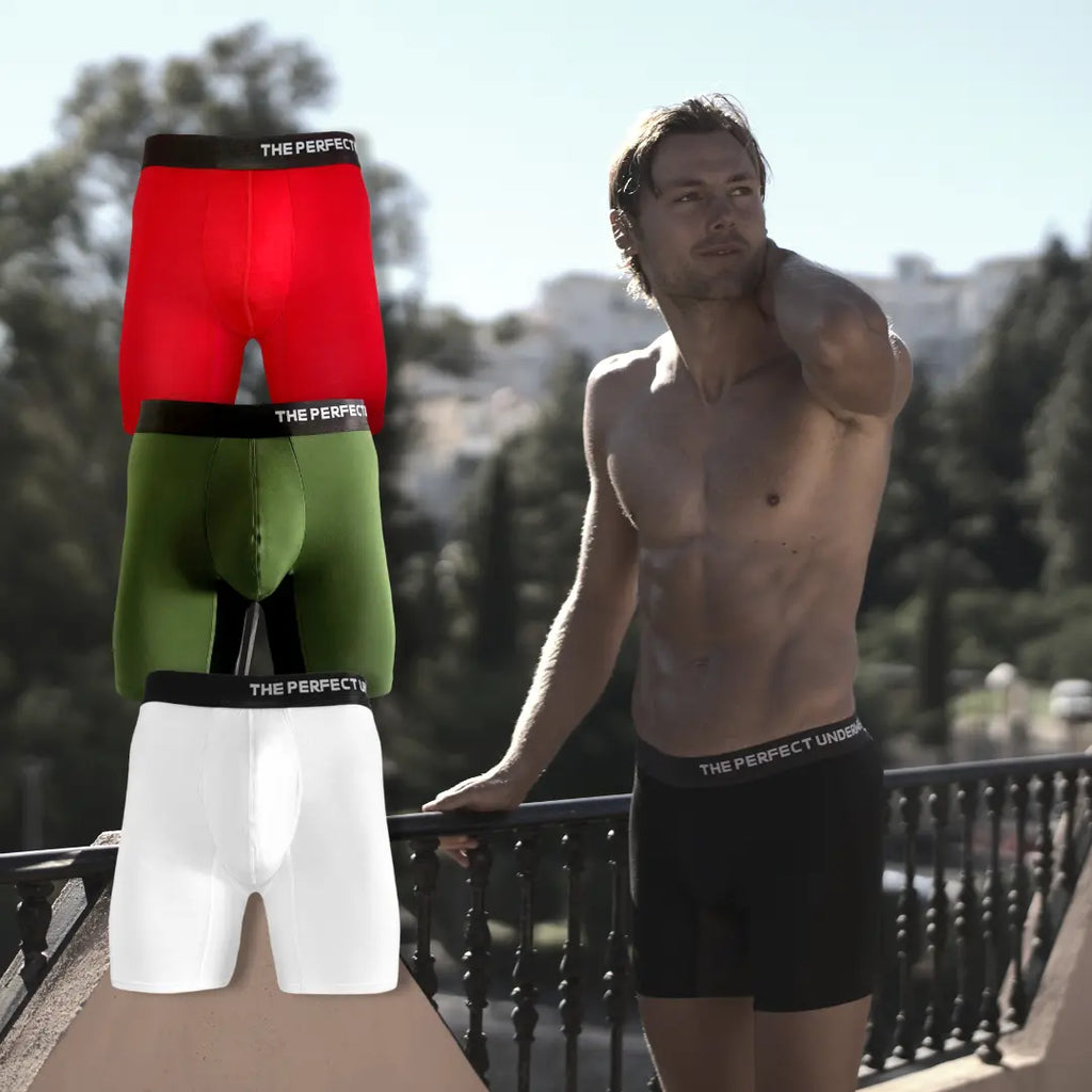 The Perfect Underwear bamboo boxer briefs in red, green, white, and black, showing stacked color variants alongside a model wearing the black pair outdoors.
